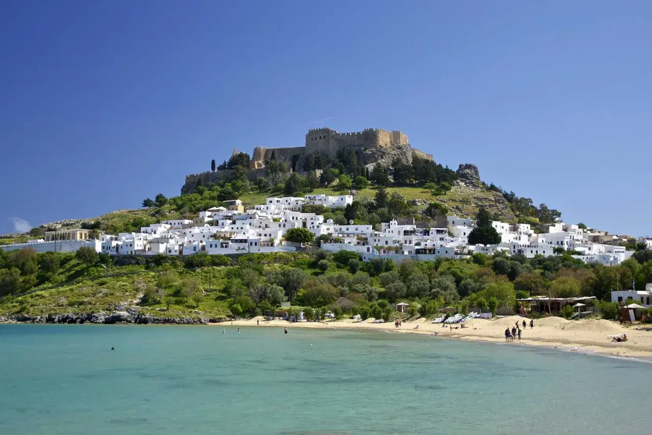 Majowa pogoda na Rodos zachwyca: białe domki Lindos, zamek na wzgórzu i turkusowe morze. Idealny czas na plażowanie.