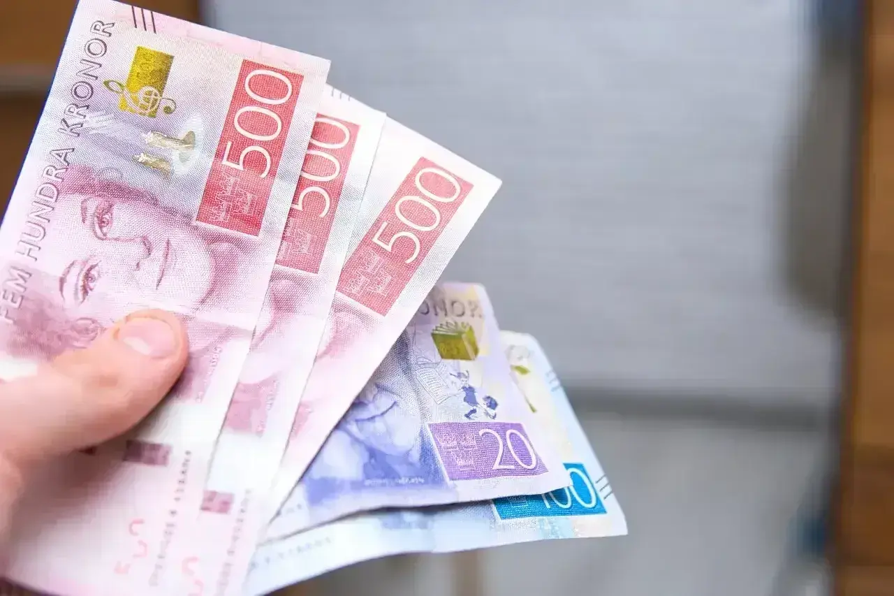 Dłoń trzyma banknoty 500 koron szwedzkich. To właśnie jaka waluta jest w Szwecji.