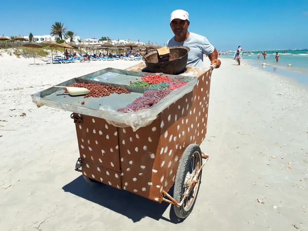 Sprzedawca na plaży w Tunezji oferuje słodycze. Może to być okazja do wymiany drobnych na pyszności, bo tunezja waluta to dinar.