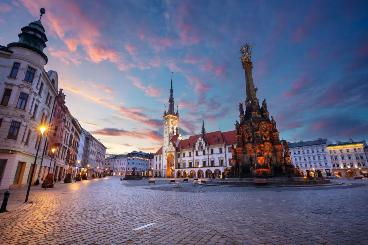 Zachód słońca nad pięknym rynkiem w Olomoucu, z widokiem na zabytkowy ratusz i Kolumnę Trójcy Świętej. Dolina Morawy wita o zmierzchu.