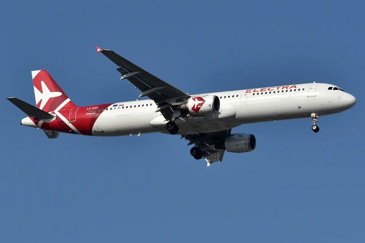 Samolot linii lotniczych Electra Airways z czerwonym ogonem i białym kadłubem leci na tle błękitnego nieba.