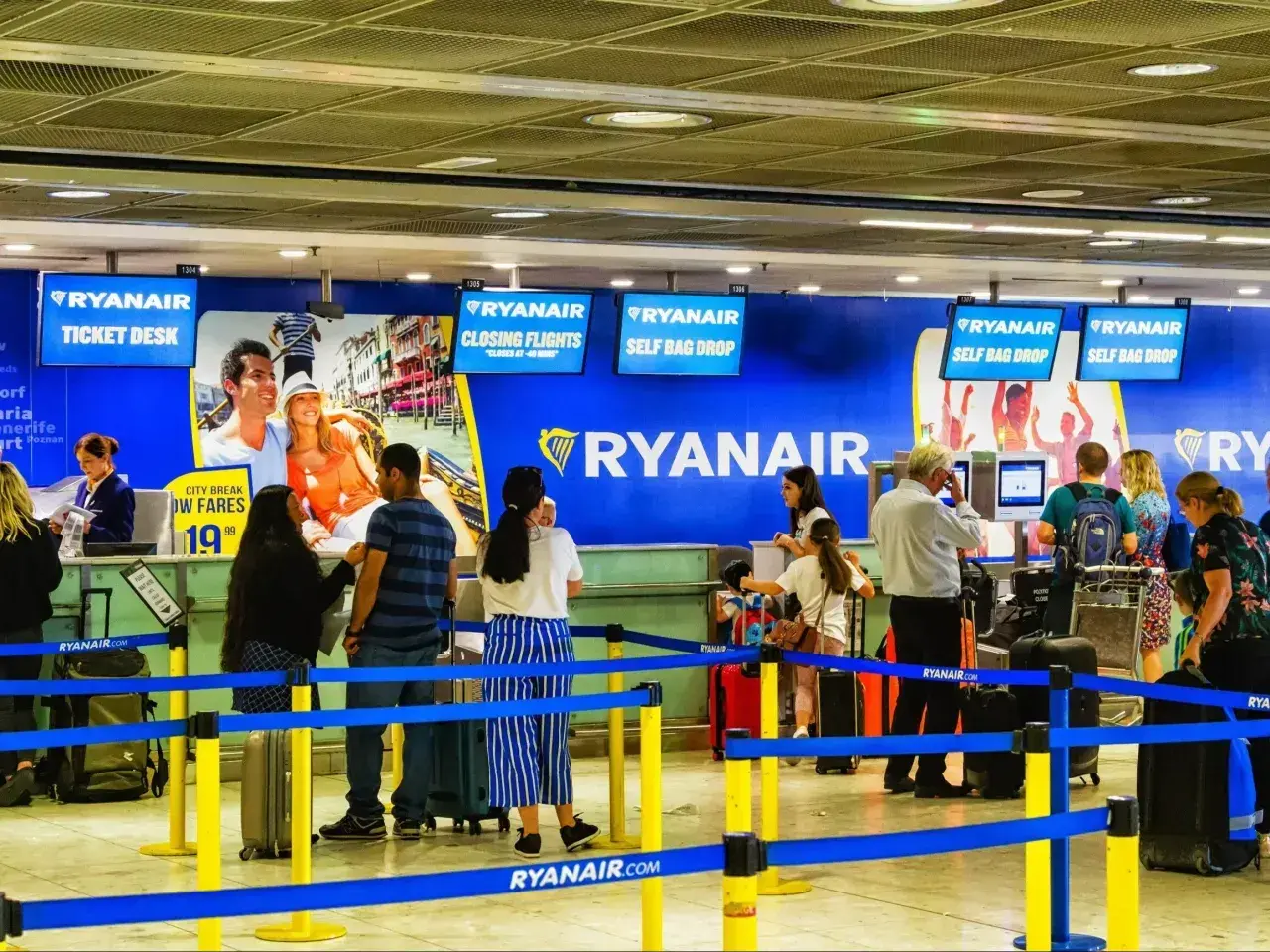 Odprawa online Ryanair ułatwia podróżowanie. Ludzie z bagażami czekają w kolejce do stanowisk odprawy.