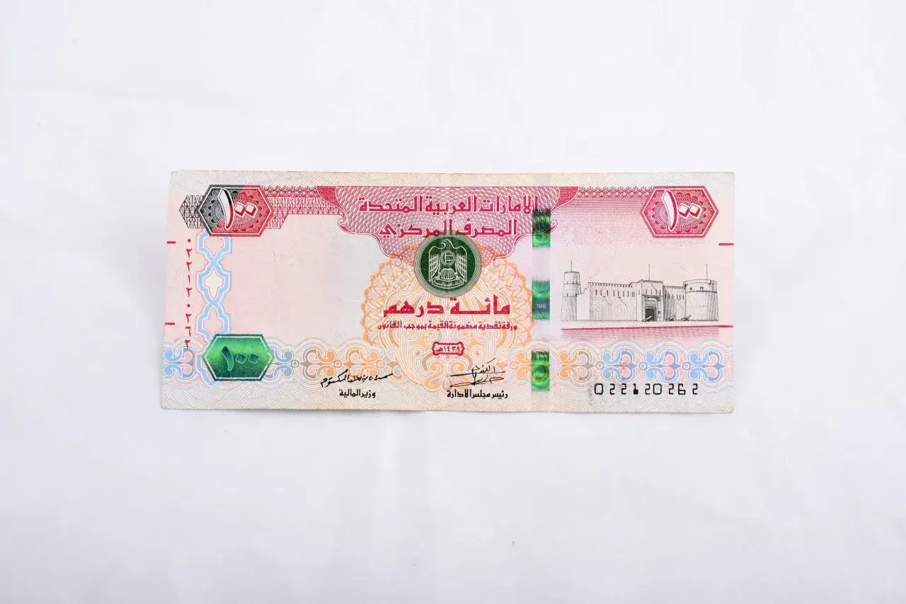 Sto dirhamów, czyli jaka waluta w Dubaju. Na banknocie widnieje zamek i herb Zjednoczonych Emiratów Arabskich.
