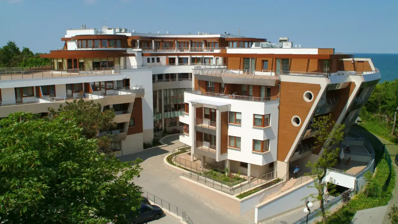 Nowoczesny kompleks hotelowy Radisson, z widokiem na morze. Kilku radisson individuals spaceruje po terenie.