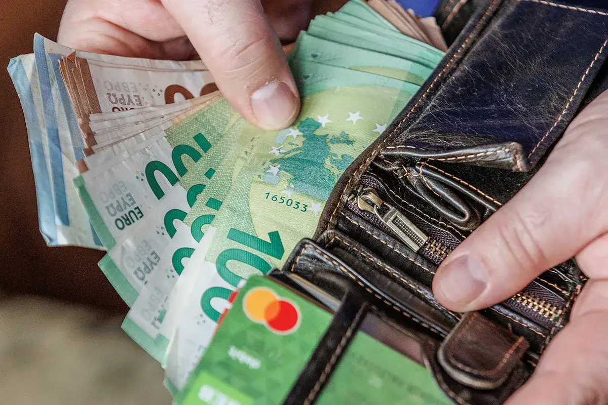 Ręka wsuwa banknoty euro do portfela. Choć Litwa używa euro, to nie jest to litewska waluta.